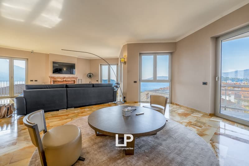 Spacious living room with large windows offering a scenic view, hardwood flooring, a round coffee table, and a comfortable sofa set. The room has a cozy and modern feel with neutral tones and elegant decor.