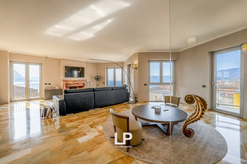 Spacious living room with large windows offering a scenic view, hardwood flooring, a modern sofa, a round dining table, and decorative elements such as a fireplace and artwork.