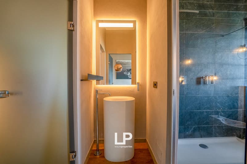 Modern bathroom with white sink, glass shower, and LP branding on the sink pedestal