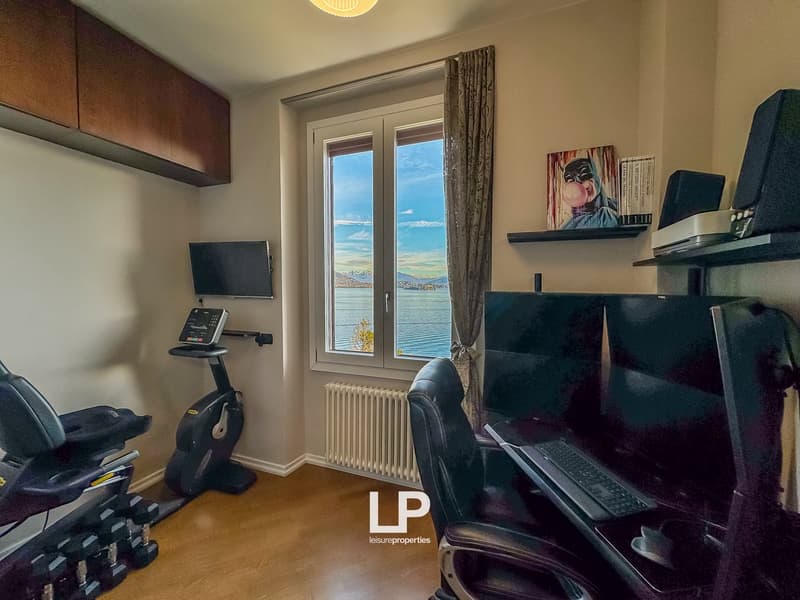 Home office with exercise equipment, desk, computer, monitor, radiator, window with view
