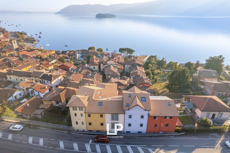 Town with multiple houses of various colors and styles, set against a backdrop of mountains and a lake.