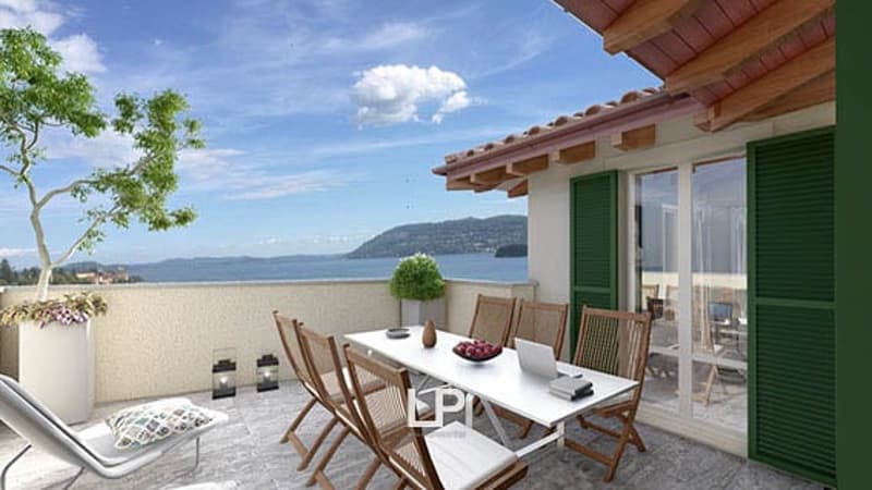 Modern balcony, table with chairs, overlooking sea, wooden railings, floor covering, trees, potted plants, lamps