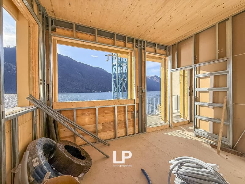 interior room under construction with wooden walls, large windows, view of mountains and lake, steel beams, open balcony