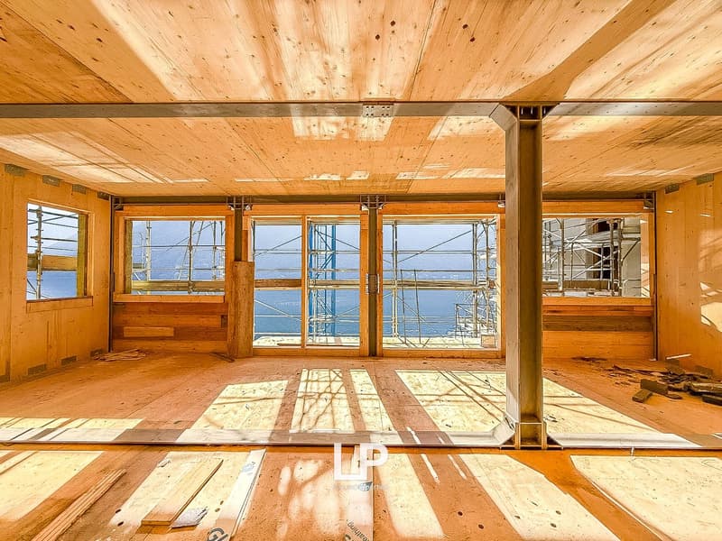 bare interior with wooden floor and beams, large windows, no furniture, under construction, large view from windows