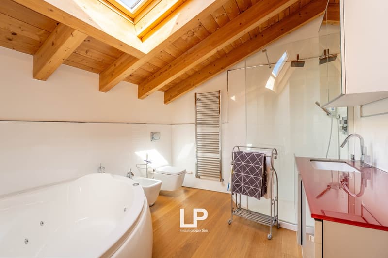 Spacious bathroom with large bathtub, glass shower, towel rack, modern design