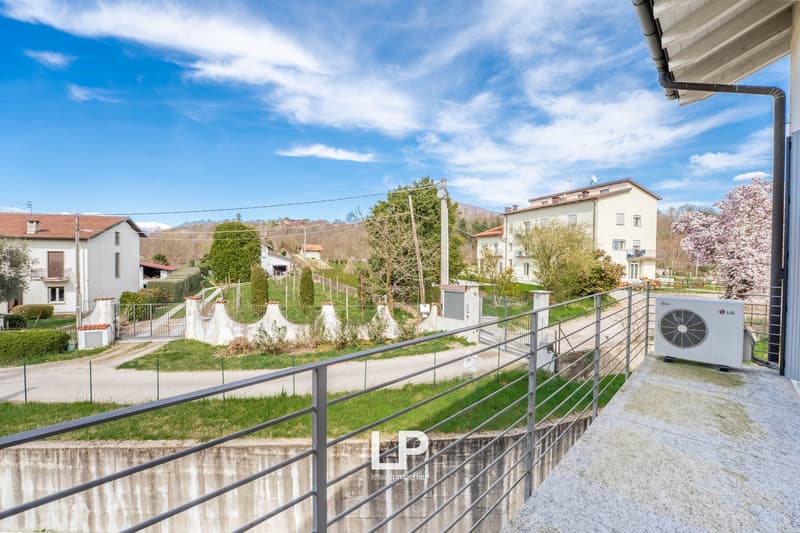 balcony with railing, white wall, trees, other houses in the background, greenery