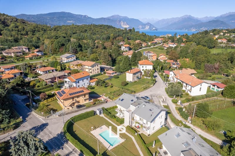 Houses with pool in a neighborhood in the mountains, surrounded by green landscape, mountains and sea in the distance.