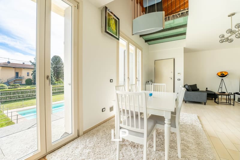 dining area with white table and chairs, rug, sliding glass doors, balcony, outdoor view with pool