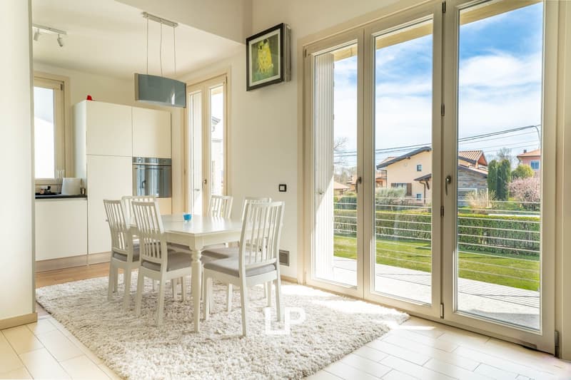 modern interior, white walls, white kitchen, white dining table, carpet, glass balcony doors, outdoor view