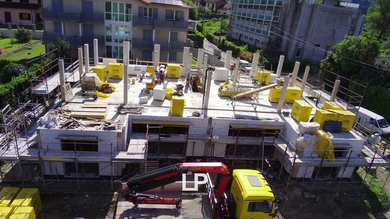 Building in construction, reinforced concrete, white material, yellow containers, construction vehicle