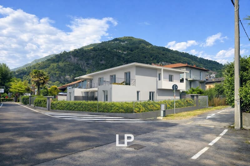 Modern 2-story house, white exterior, multiple balconies, fenced garden, mountain view