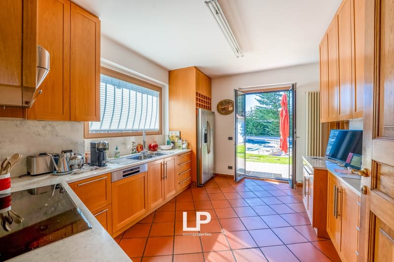 Spacious kitchen with wooden cabinets, stainless steel appliances, tile flooring, and a sliding glass door leading to an outdoor area
