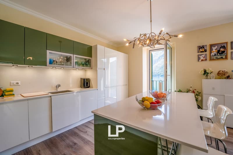 white cabinets, island with bar stools, modern lighting, window with balcony access, view, large sink, white countertops