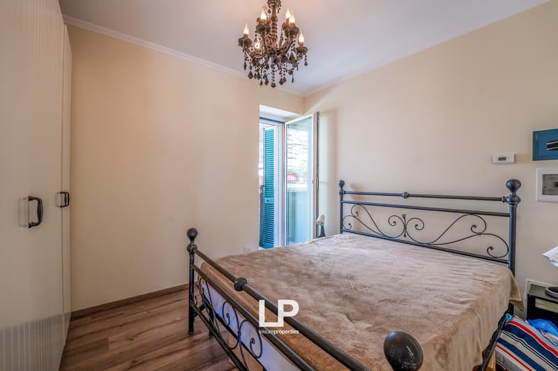 bed, chandelier, balcony with window and shutters, wooden floor, white walls, wardrobe