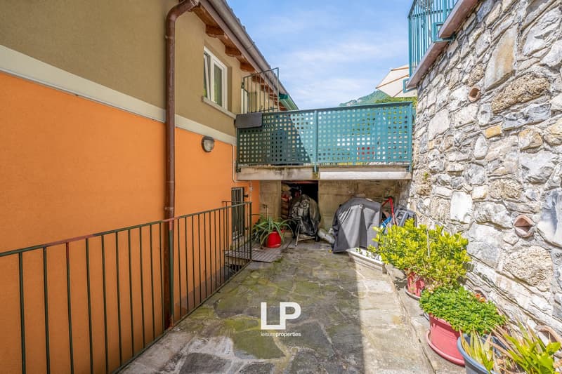 2-story house with stone exterior, balcony, storage area underneath, and potted plants