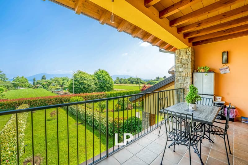 Spacious balcony with a scenic view of the surrounding gardens and mountains, wooden beamed ceiling, stone walls, outdoor dining area