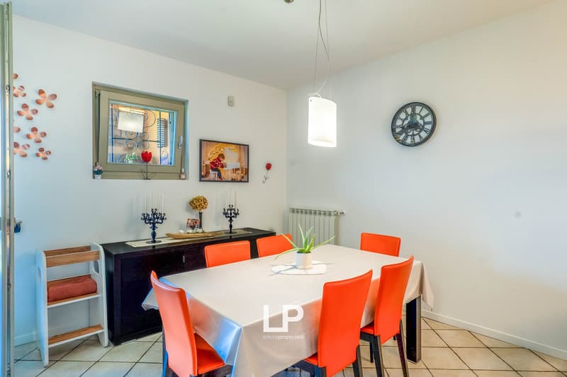 Dining table with white tablecloth, 6 orange chairs, black sideboard, wall decor, pendant light fixture