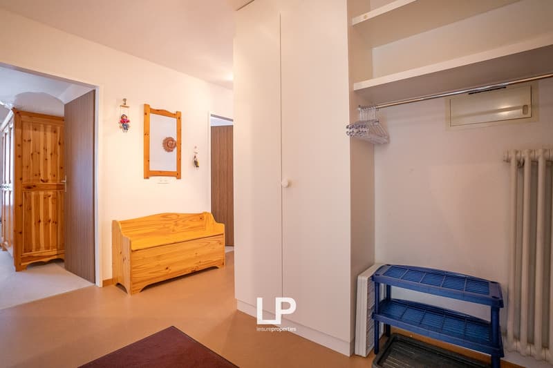 Spacious bedroom with wooden furniture, including a storage bench, and a closet. The room also features a private washing machine and a blue storage rack.