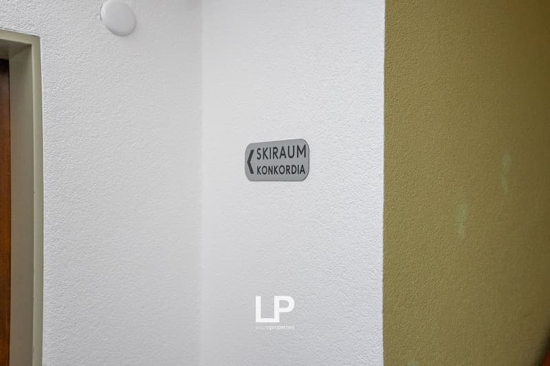 White wall with a gray sign that reads 'SKIRAUM KONKORDA' in a corner.