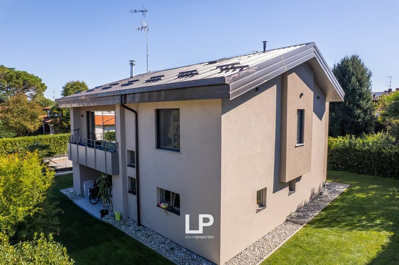 2 story house, beige exterior, metal roof, balcony on first floor, gravel around the house