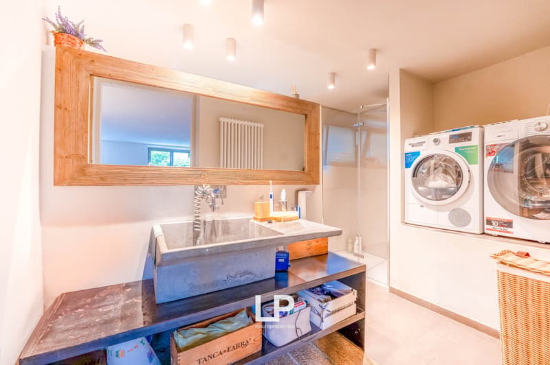 Spacious laundry room with a concrete sink vanity, large mirror, washing machine and dryer, and storage shelves