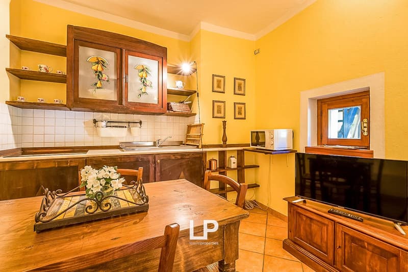 Rustic wooden kitchen with shelves, framed artwork, tile backsplash, wooden table, and appliances including a dishwasher
