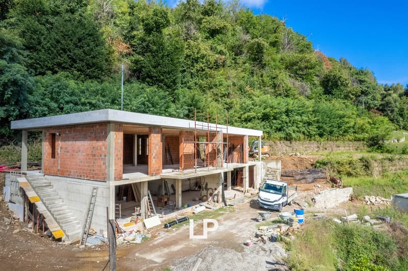 2 story house, red brick, raised ground floor, in construction, surrounded by nature