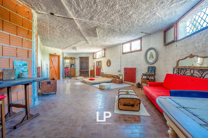 open space room, brick walls, wooden flooring, wooden furniture, red couch, red pillows, storage box, wooden table, white floor space, radiators