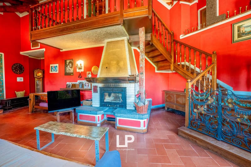 red walls, tiled floor, wooden staircase, balcony above, fireplace, TV, bench seats, wooden desk, decorative items