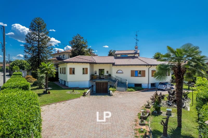 two-story house, tiled roof, white walls, large driveway, car parked, garden, plants, palm tree