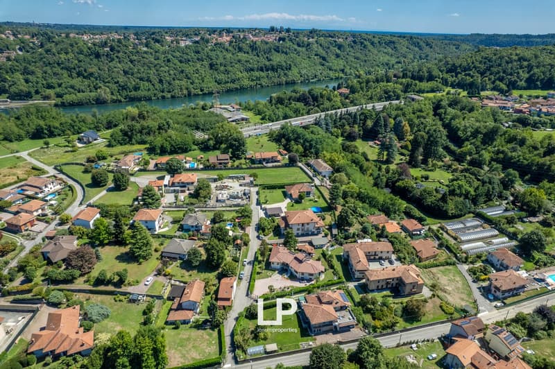 Multiple residential properties, various house designs, lush greenery, pool, nearby river, suburban setting