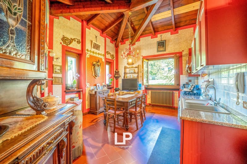 open kitchen and dining area, tiled floor, wooden beams ceiling, red walls, table, chairs, wooden cabinet, radiator, tv, wall decor, dining room lamp
