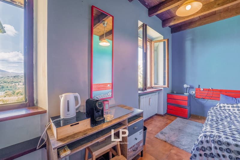 bedroom with desk, electric kettle, coffee machine, bed, radiator, large mirror, window with scenic view, ceiling lamp