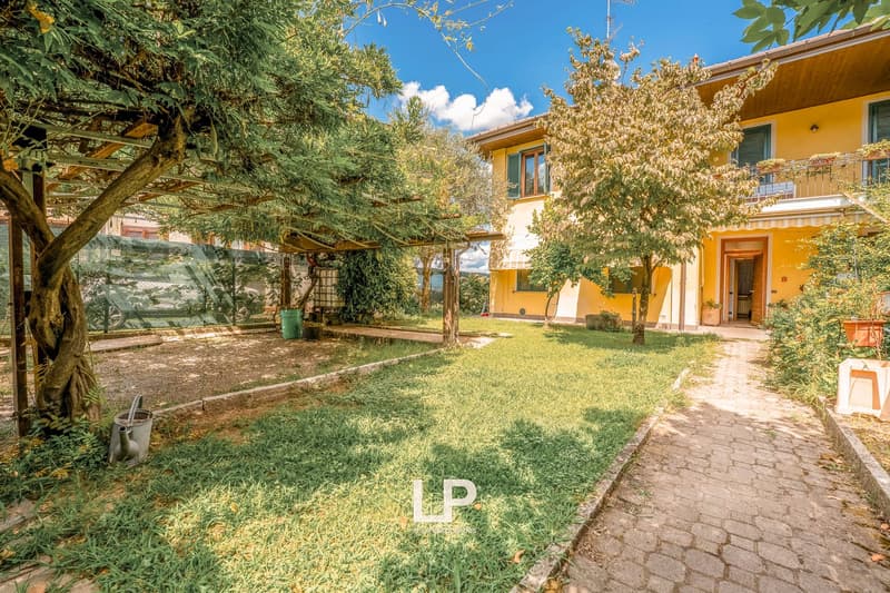 two story house, yellow exterior, large yard, trees, paved path, front door