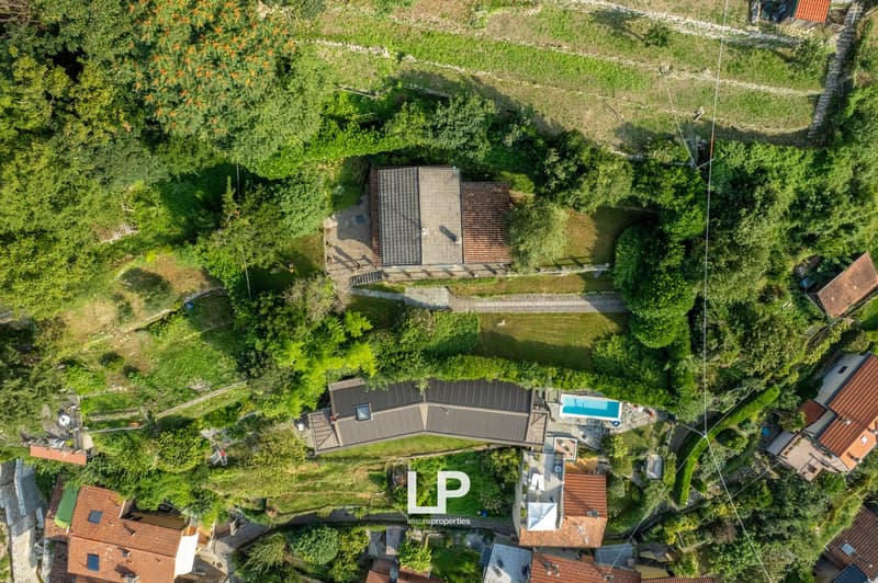 2 residential houses, swimming pool, garage, red roof tiles, surrounded by trees, located on a slope