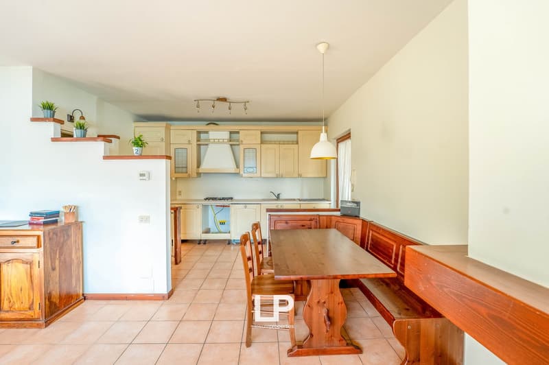 wooden countertops, white cabinetry, white tiled floor, gas stove, sink, wooden dining table and chairs, wooden bench