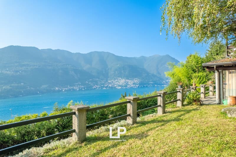 elevated grassy area, concrete fence, view of lake and mountains