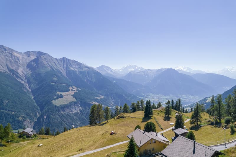 Wooden house, tiled roof, near mountains, farm machinery, clear view of mountains and sky, distant trees and house