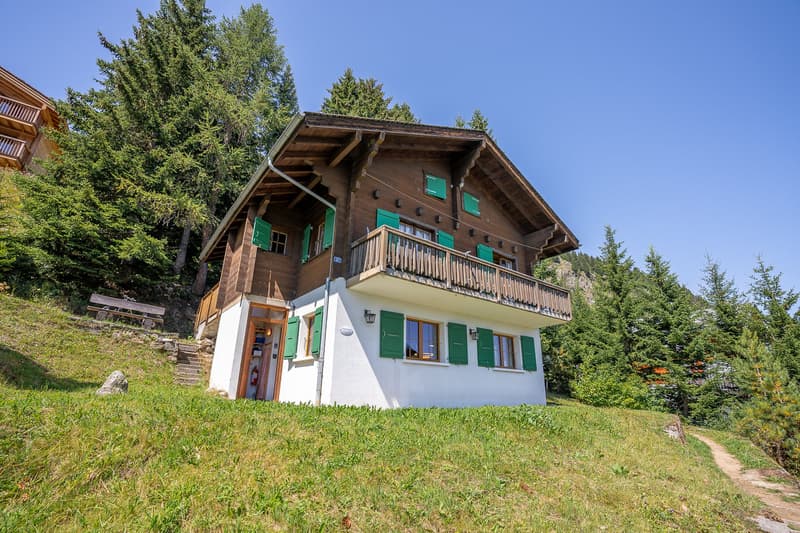 two-story house, wooden exterior, green shutters, wooden balcony, white base, small garden with path