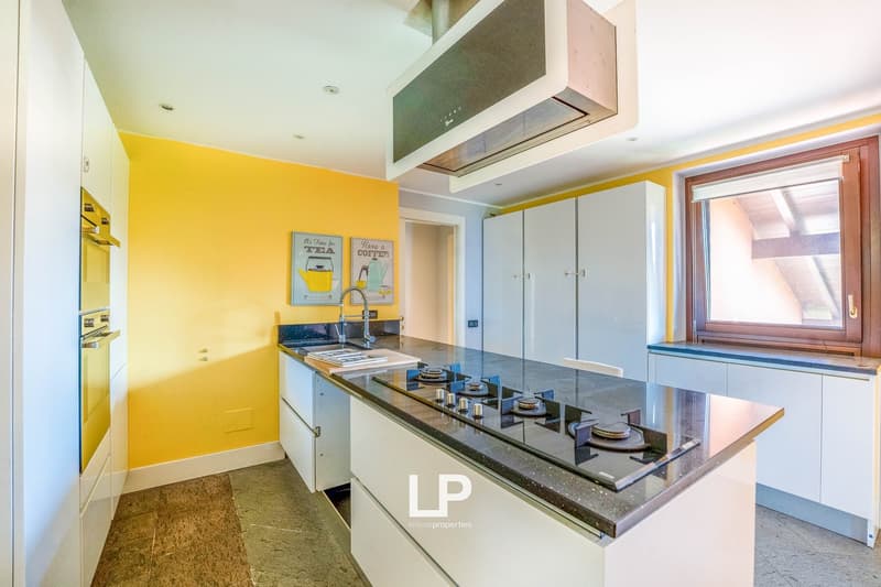 Modern kitchen, yellow wall, white countertops, gas stove, sink, kitchen cabinets, framed picture on wall, large window, tiled floor