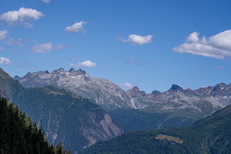 majestic mountains with snowy peaks, green forest, blue sky with clouds