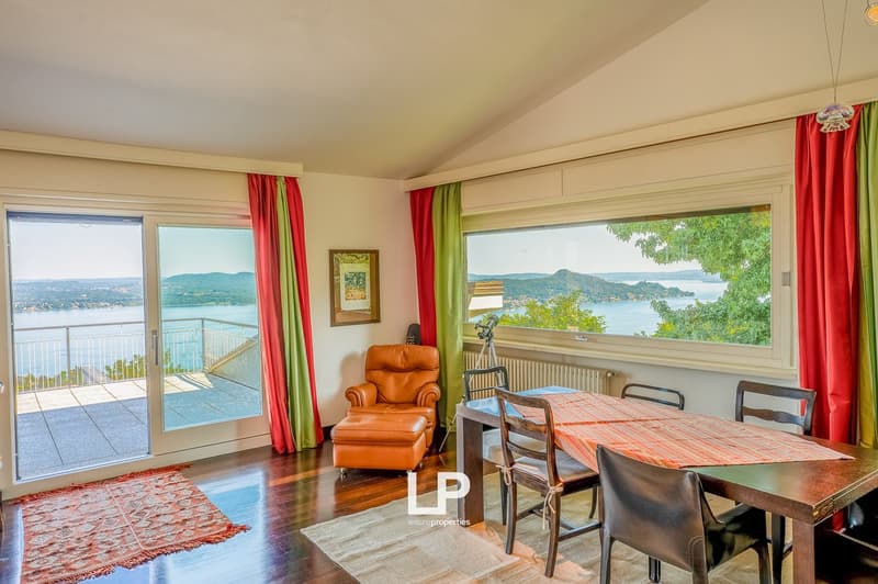 modern wooden dining table and chairs, sliding glass doors leading to a balcony, rug, panoramic view of the lake and mountains