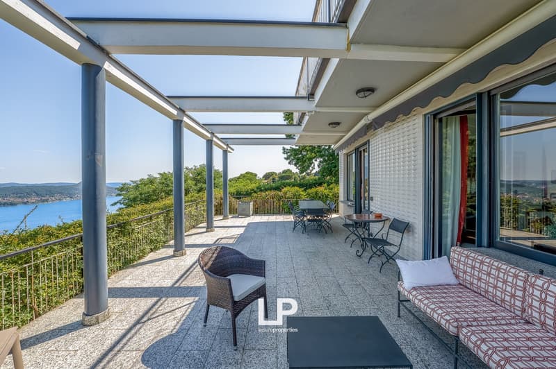Oversized terrace with table and chairs, water view, covered structure