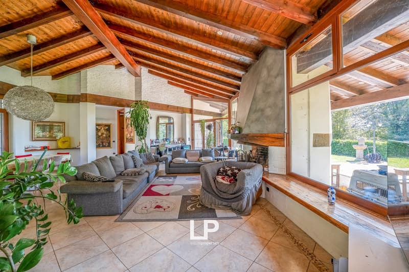 tiled floor, exposed wooden ceiling, fireplace, large windows with view, couches, rug, armchair