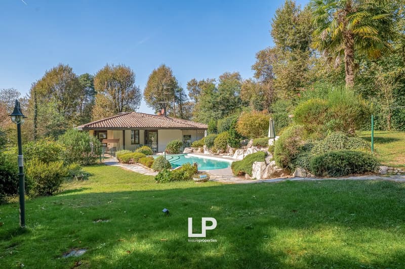 Detached house with swimming pool, surrounded by a well-maintained garden with various plants and trees