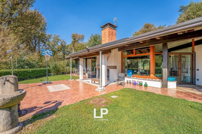 modern house, brick chimney, large windows, brick patio, basketball hoop, outdoor bench, outdoor fireplace