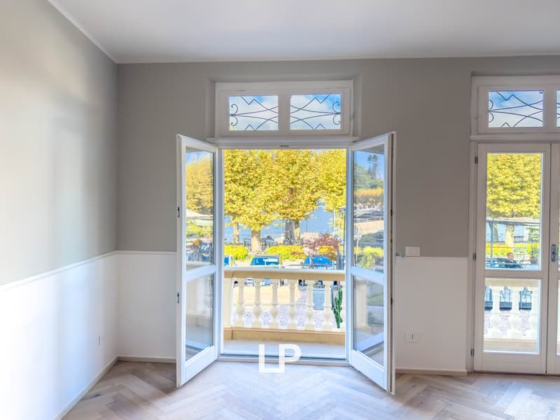 Open balcony doors, parquet floor, large windows, balcony railing, lake view