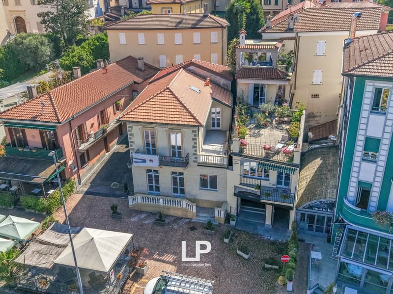 multi-building complex with tiled roofs, multiple balconies, ground-floor terraces, and multiple outdoor seating areas