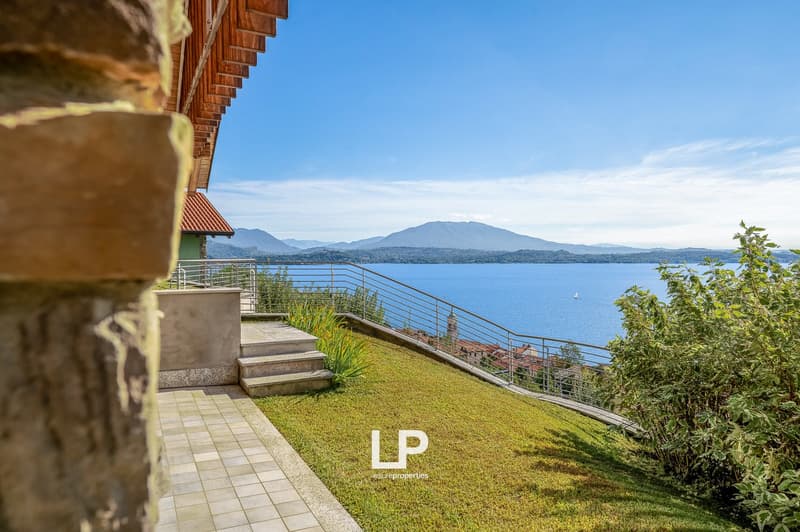 elevated ground, wooden deck, metal railings, stairs leading to grassy slope, view of lake, mountains in distance
