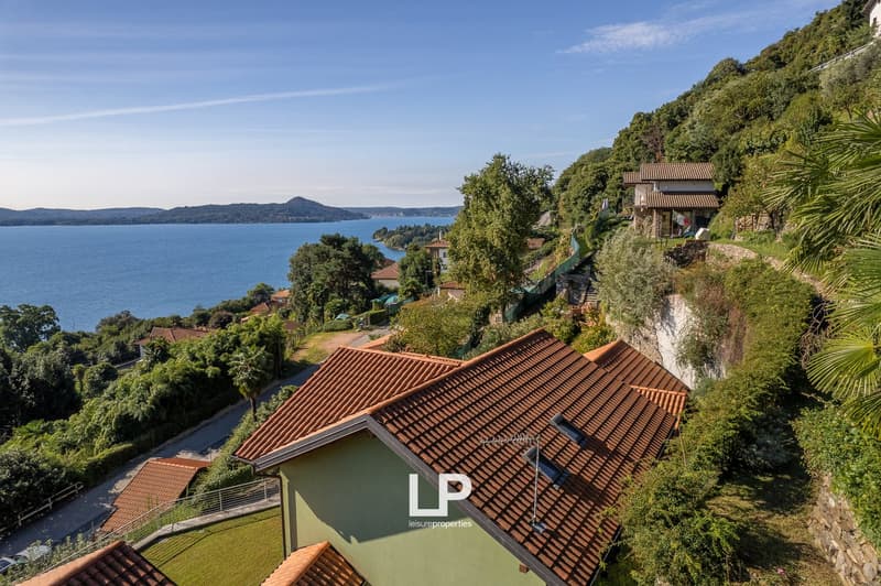 House on a hill, brown tiled roof, lake and mountains in the background